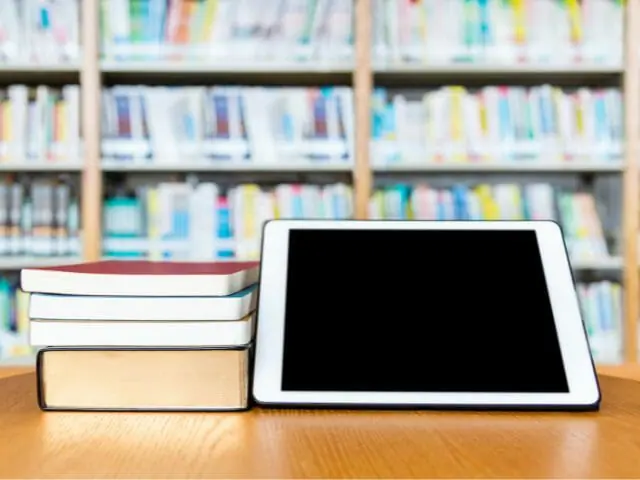 digital tablet and wooden books on table