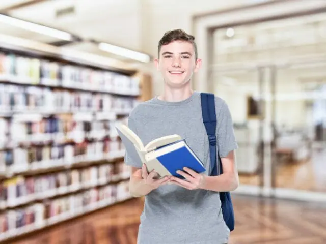 male student smiling and holding book