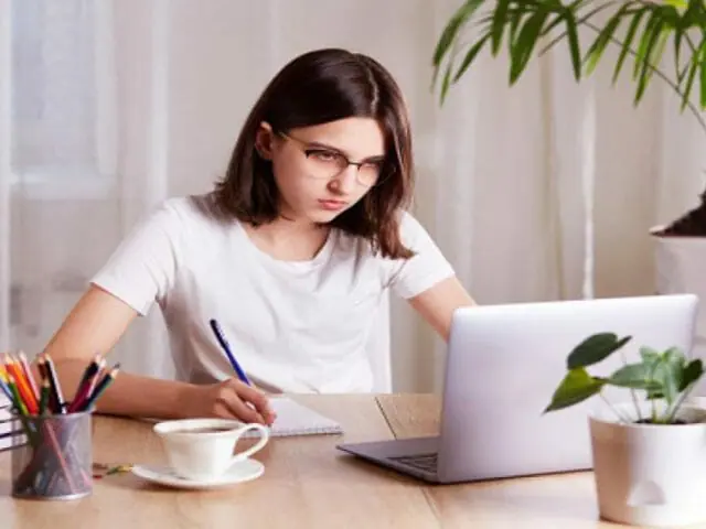 teenage girl writing and using a laptop